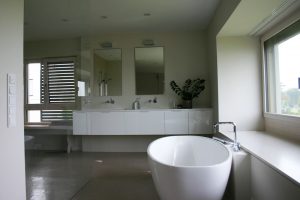 Masterbad mit ovaler Badewanne, dualer Waschtischanlage und zwei Wandspiegeln